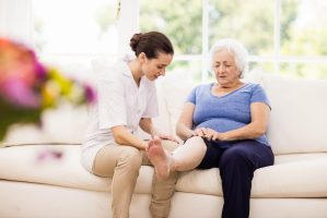 Physiotherapist taking care of sick elderly patient at home